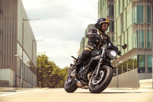 Three-quarter front angle of a person riding a motorcycle on the street. opens in a new window