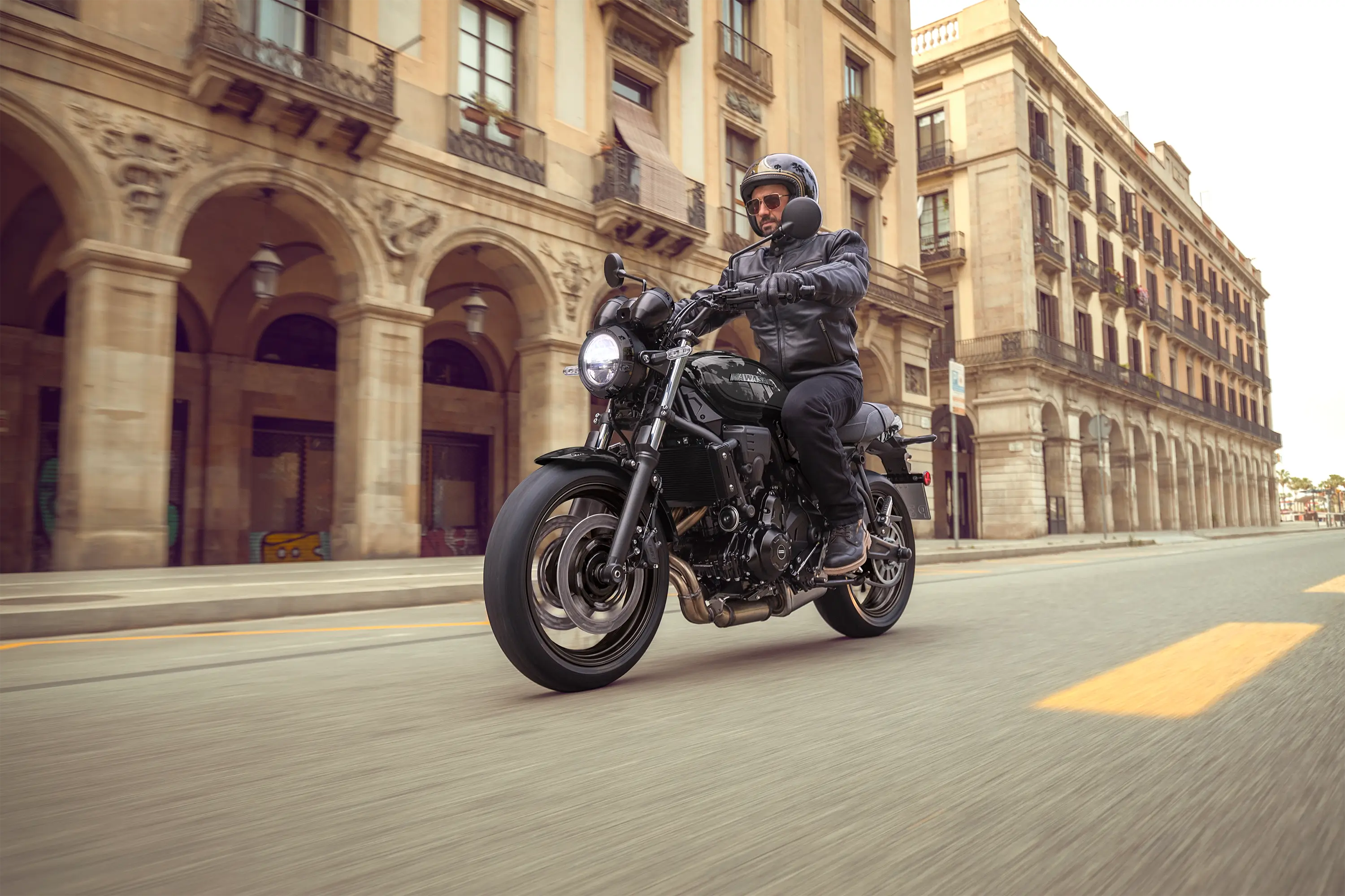 Three-quarter front angle of a person riding a motorcycle on the street.