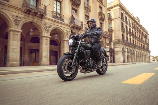 Three-quarter front angle of a person riding a motorcycle on the street. opens in a new window