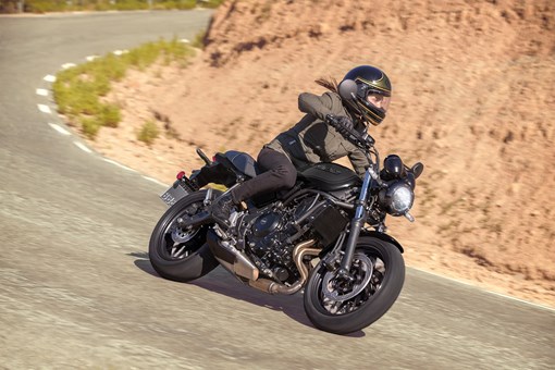 Three-quarter front angle of a person riding a motorcycle on a highway. opens in a new window