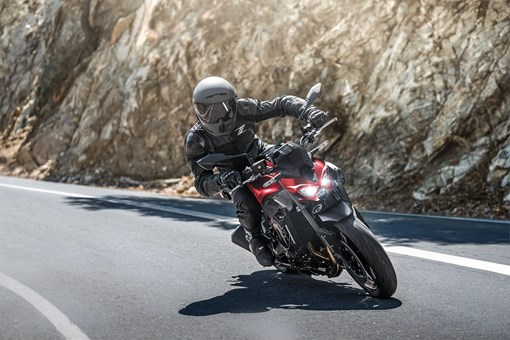 Three-quarter front angle of a person riding a motorcycle on a highway. opens in a new window