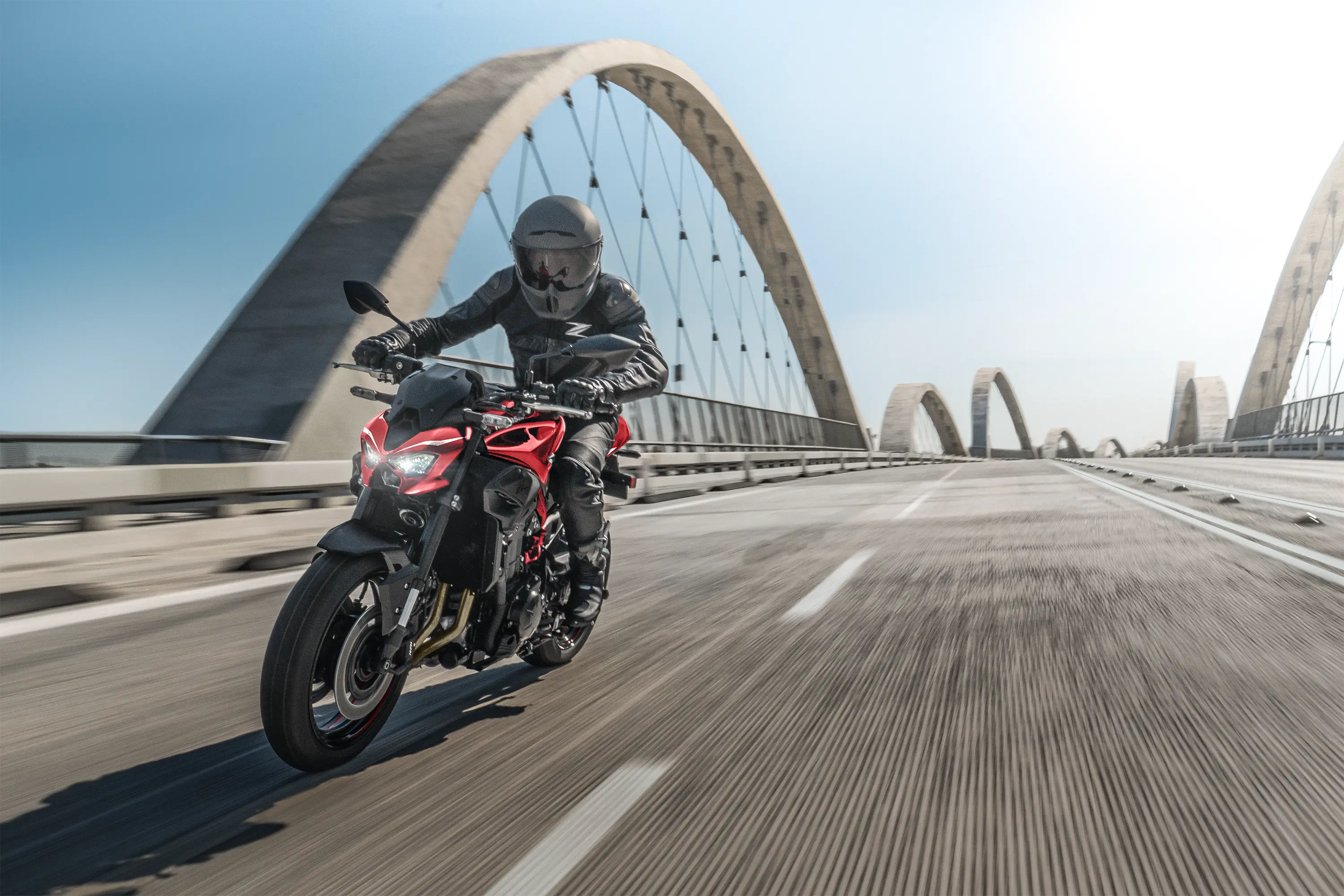 Three-quarter front angle of a person riding a motorcycle on a bridge.