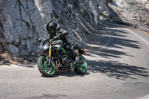 Three-quarter front angle of a person riding a motorcycle on a canyon. opens in a new window
