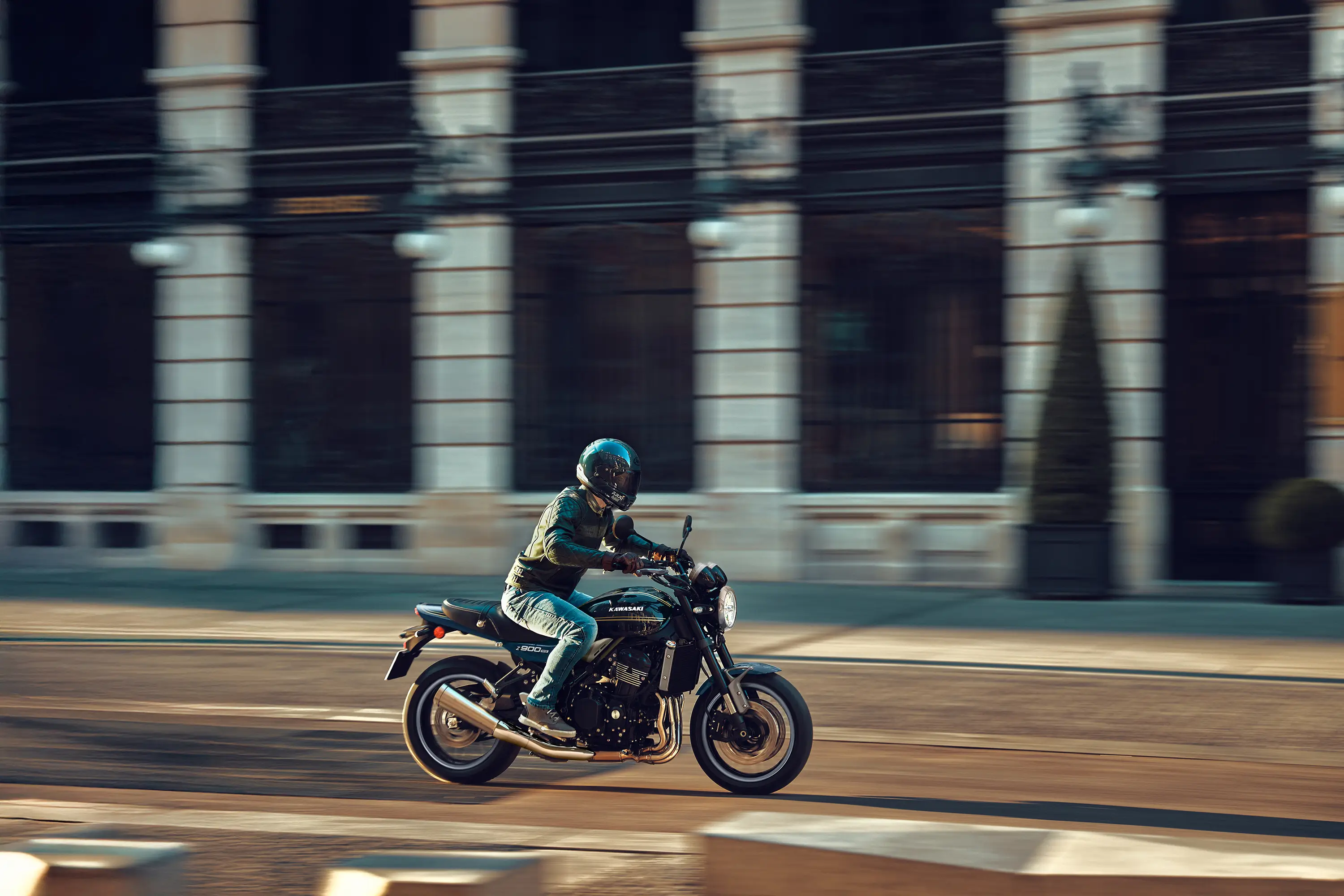 Side angle of a person riding a motorcycle on a town road.