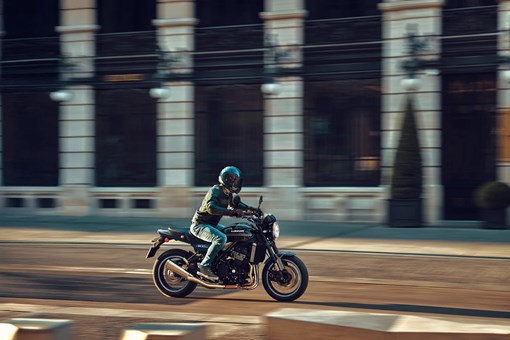 Side angle of a person riding a motorcycle on a town road. opens in a new window