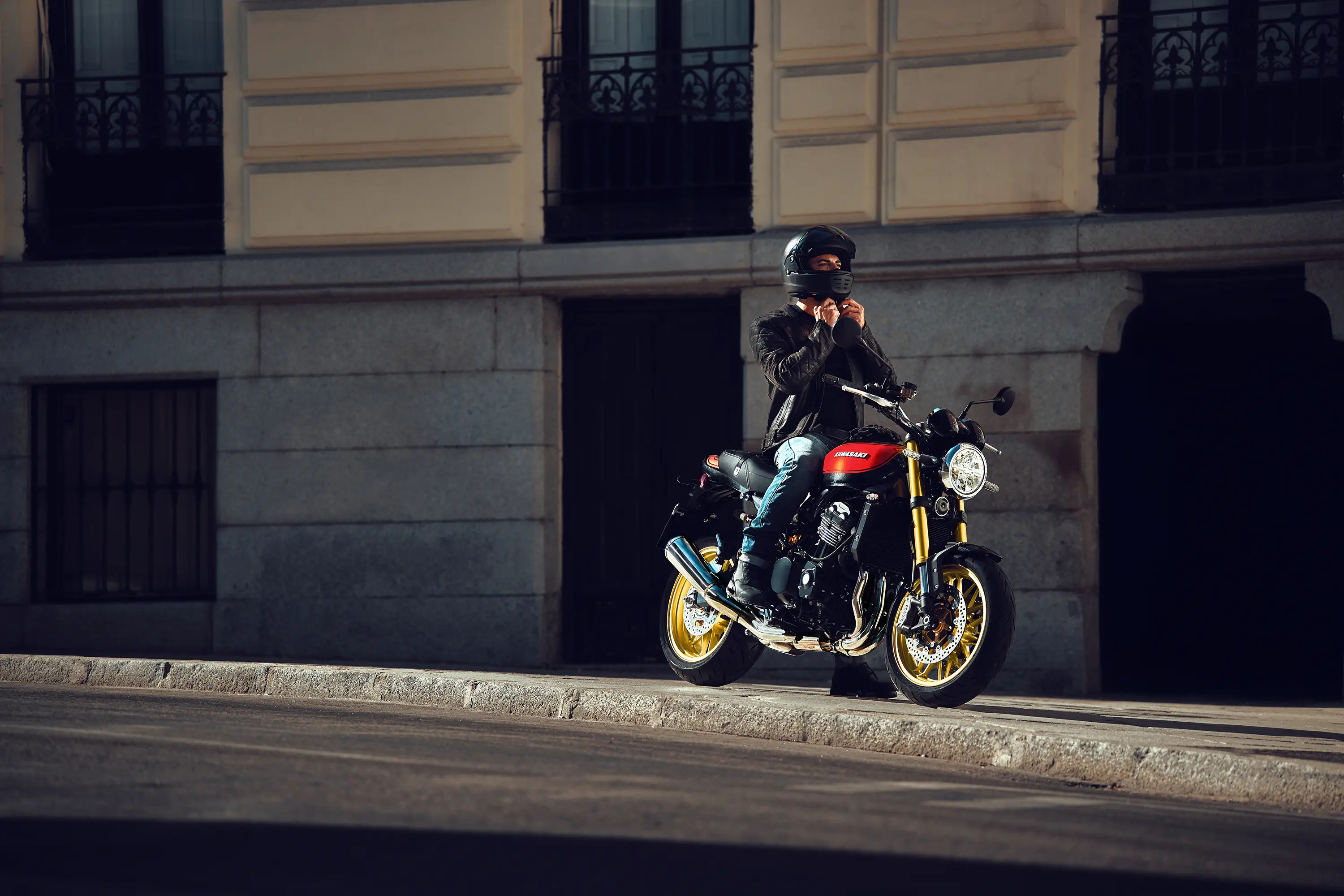 Side view of a person seated on a motorcycle on a city street.