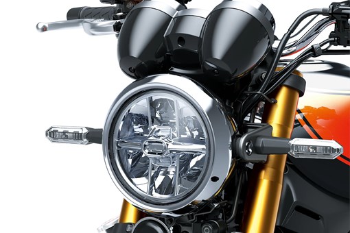 Close-up of the headlight of a motorcycle staged in a white studio background. opens in a new window