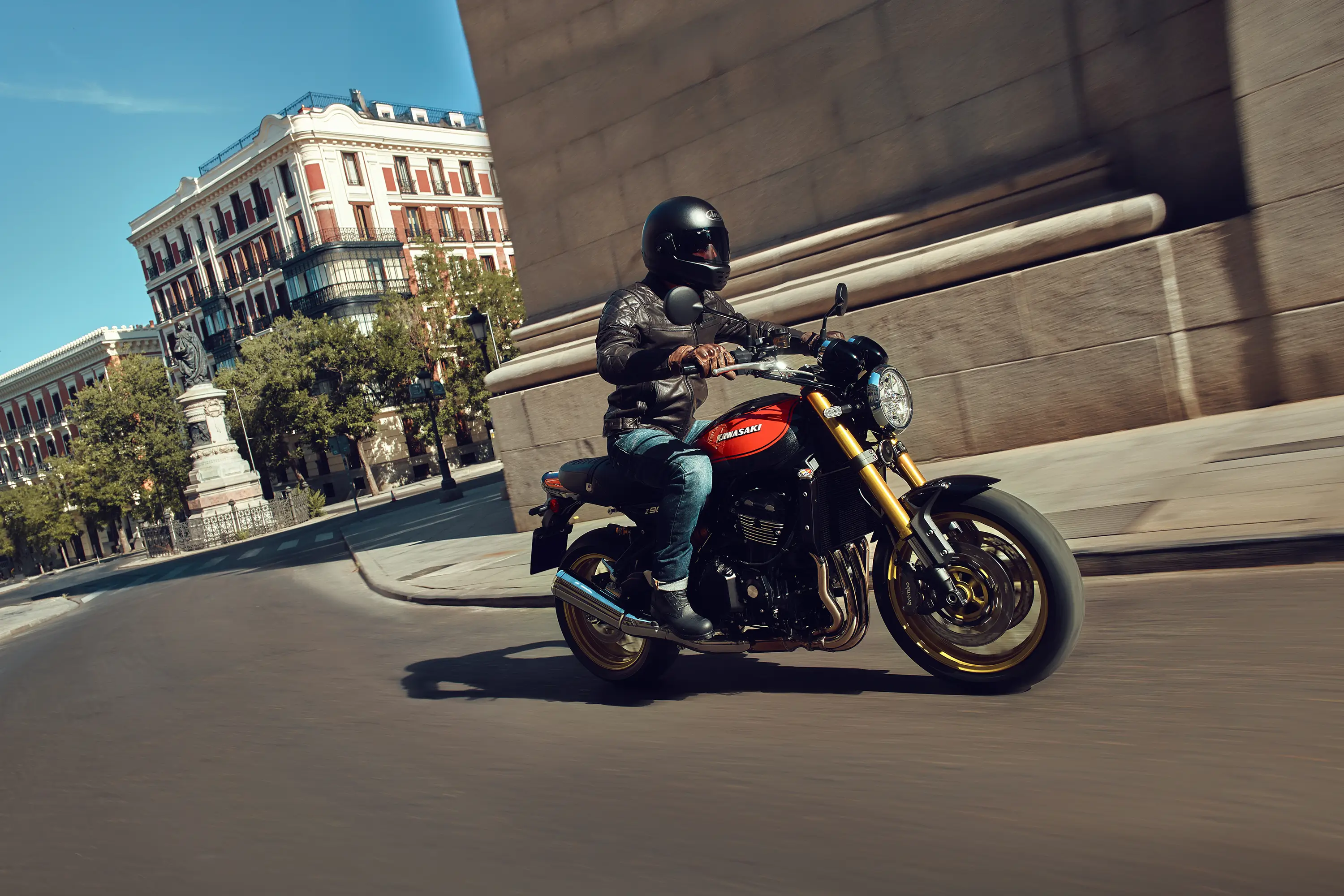 Side view of a person riding a motorcycle on a city street.