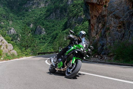 Three-quarter front angle of a person riding a motorcycle around a corner. opens in a new window