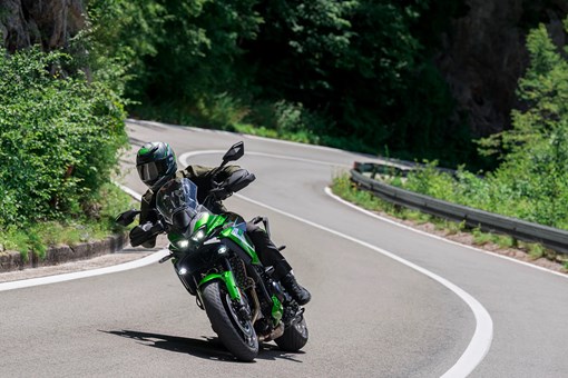 Three-quarter front angle of a person riding a motorcycle on a highway. opens in a new window
