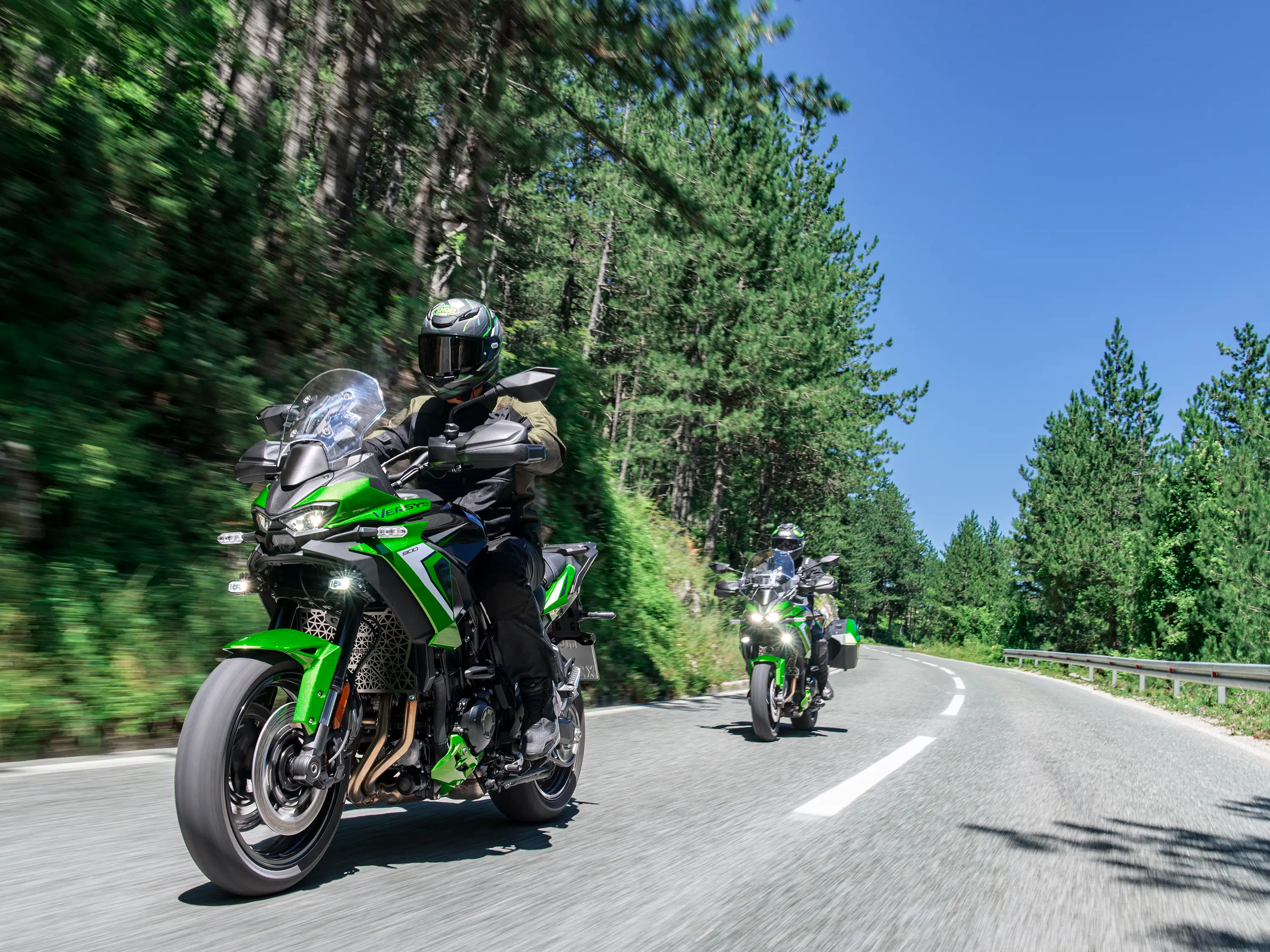Three-quarter front angle of two people riding motorcycles on a highway.