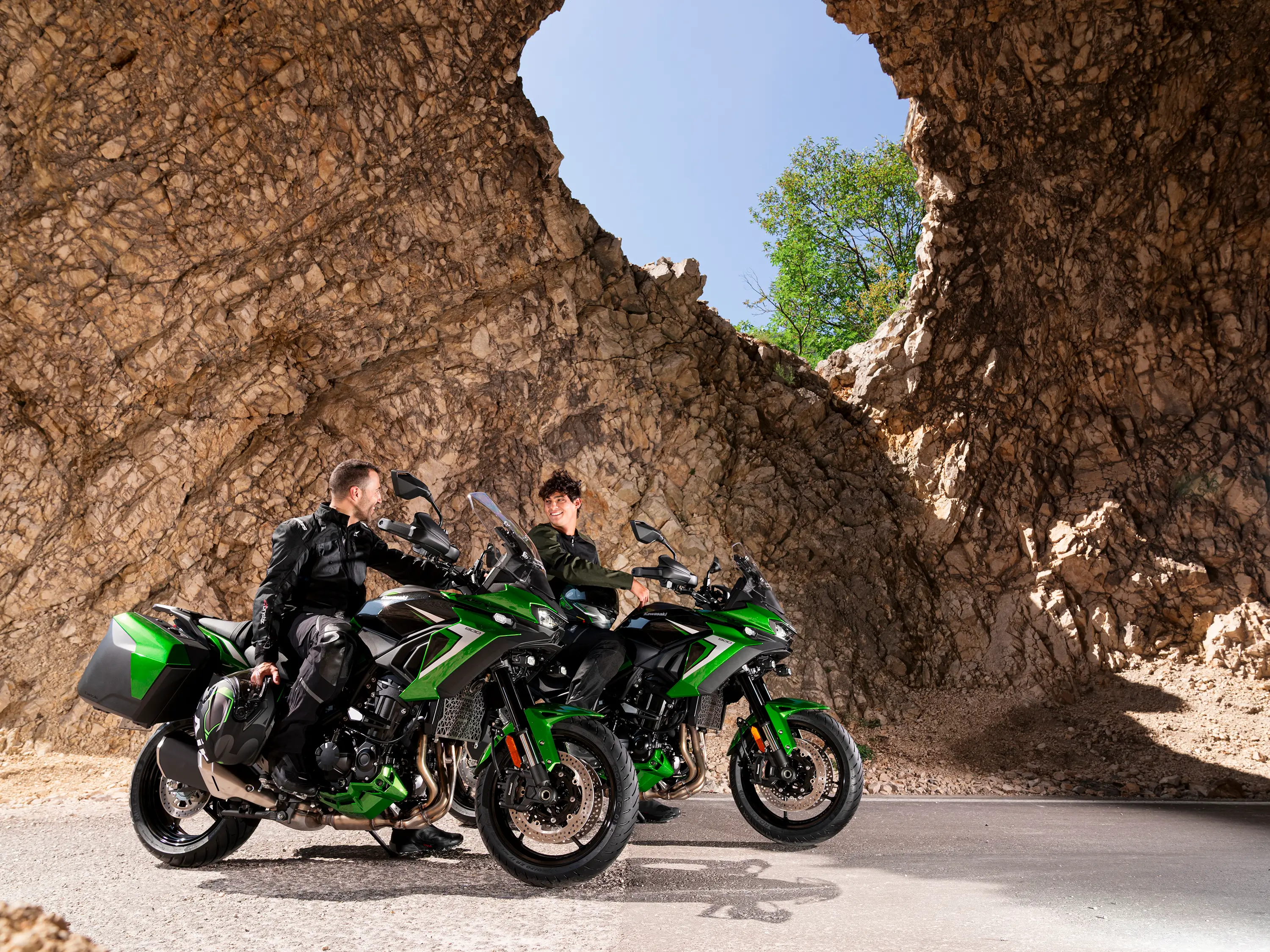 Three-quarter front angle of two motorcycles parked with riders.