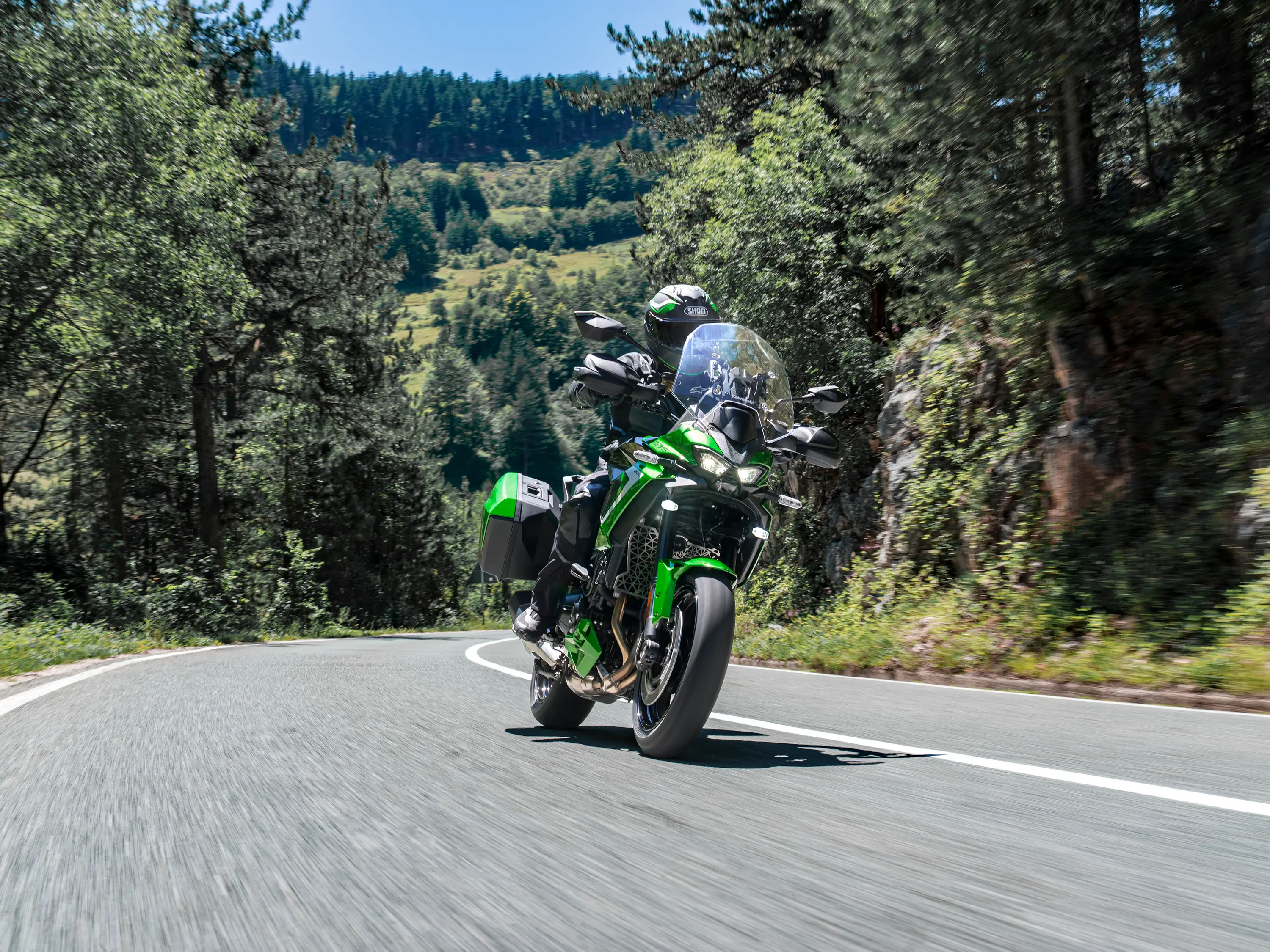 Front three-quarter angle of a person riding a motorcycle on a highway.
