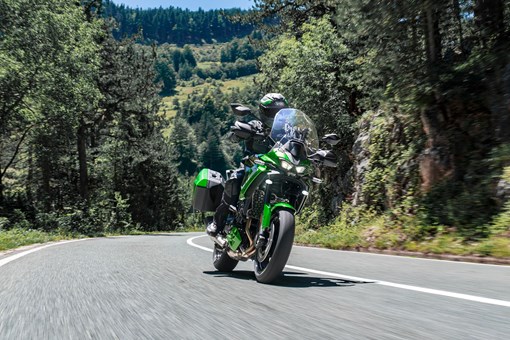 Front three-quarter angle of a person riding a motorcycle on a highway. opens in a new window