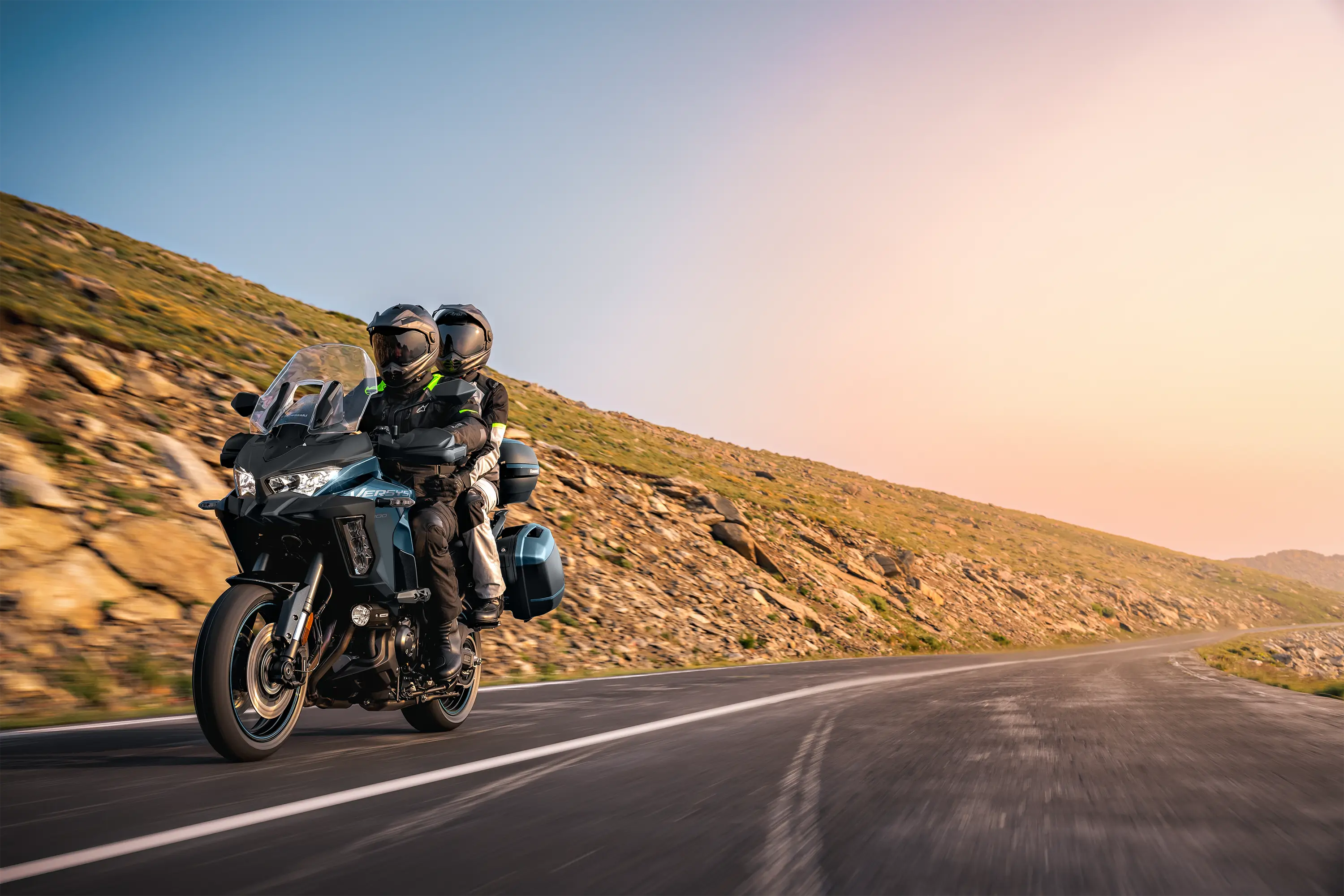 Three-quarter front angle of a person and a passenger riding a motorcycle on a highway.