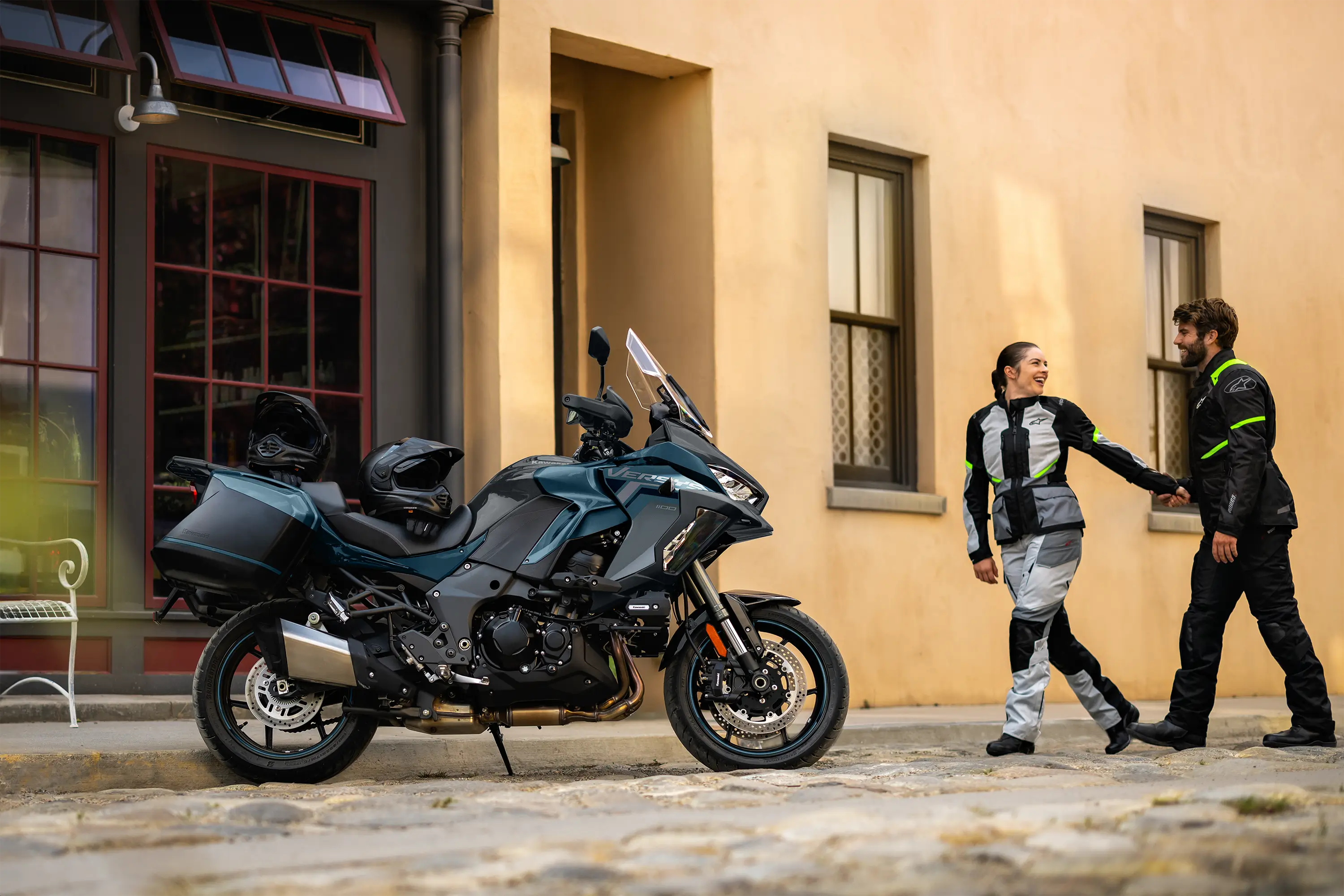 Side angle of a parked motorcycle with people in the background walking.