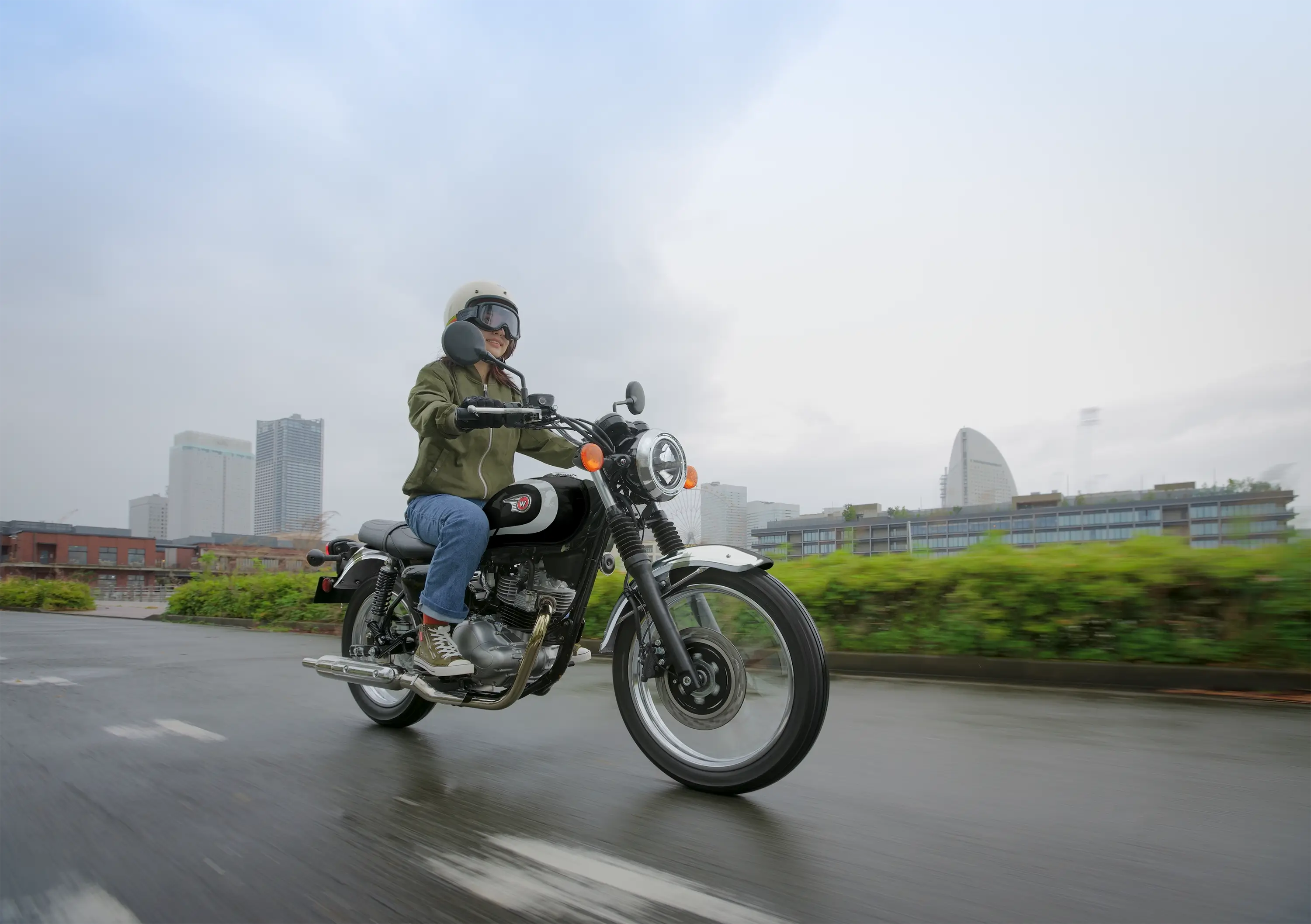 Three-quarter front angle of a person riding a motorcycle on the street.
