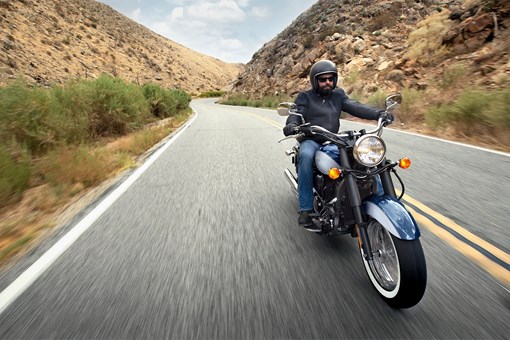 Front three-quarter angle of a person riding a motorcycle on a highway. opens in a new window