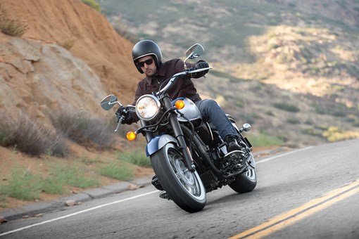 Three-quarter front angle of a person riding a motorcycle on a highway. opens in a new window