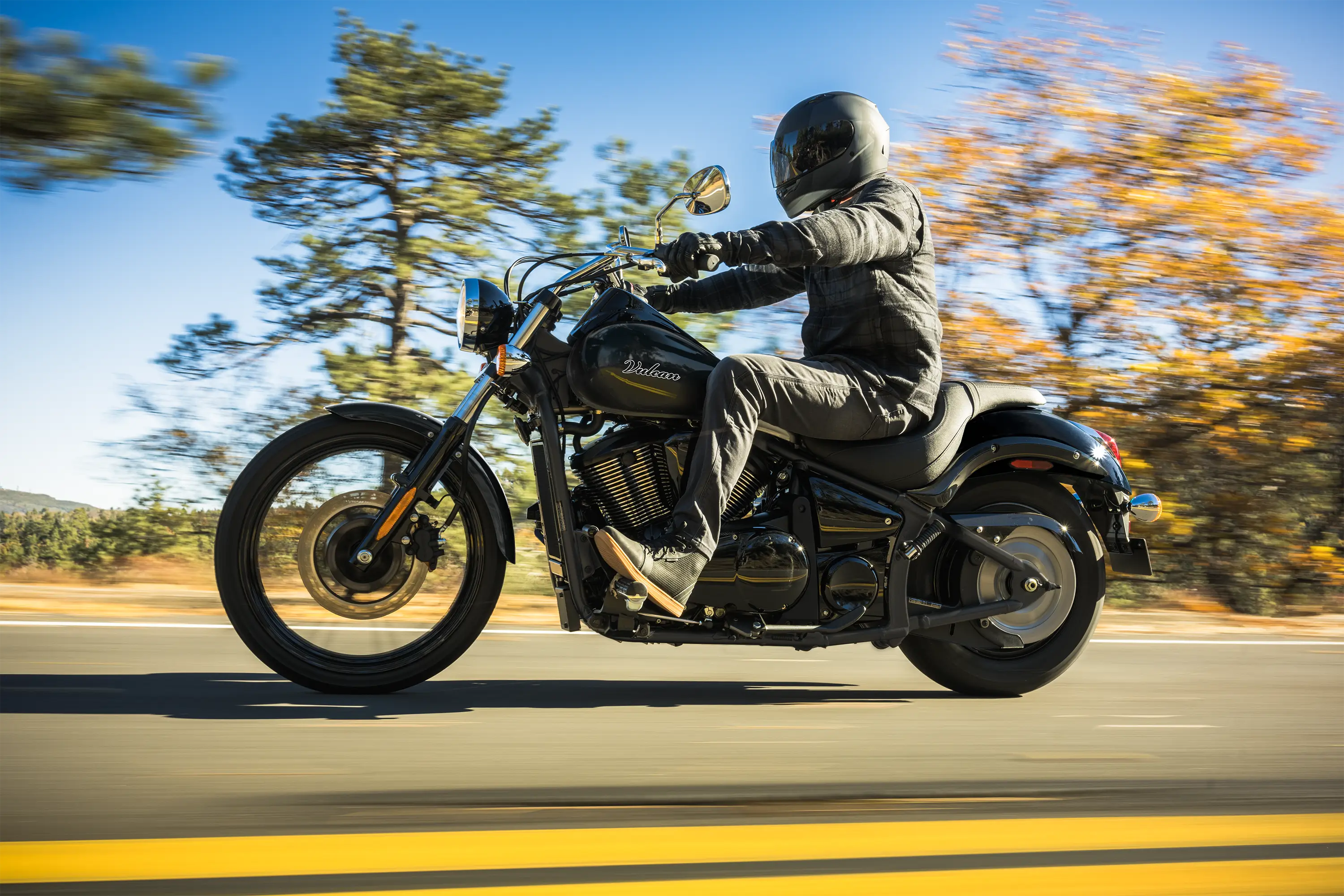 Side angle of a person riding a motorcycle on a highway.