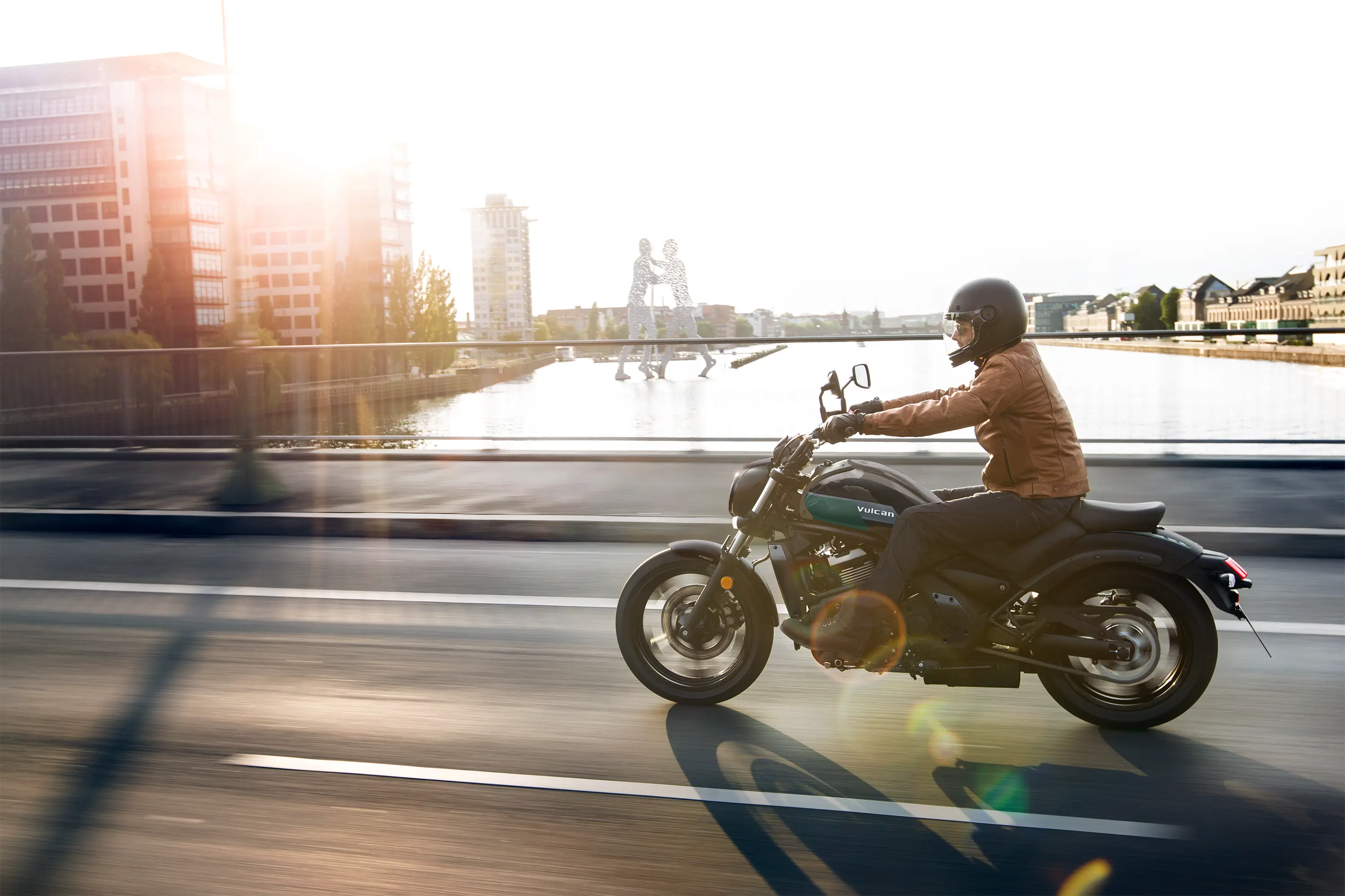 Side angle of a person riding a motorcycle on the street.