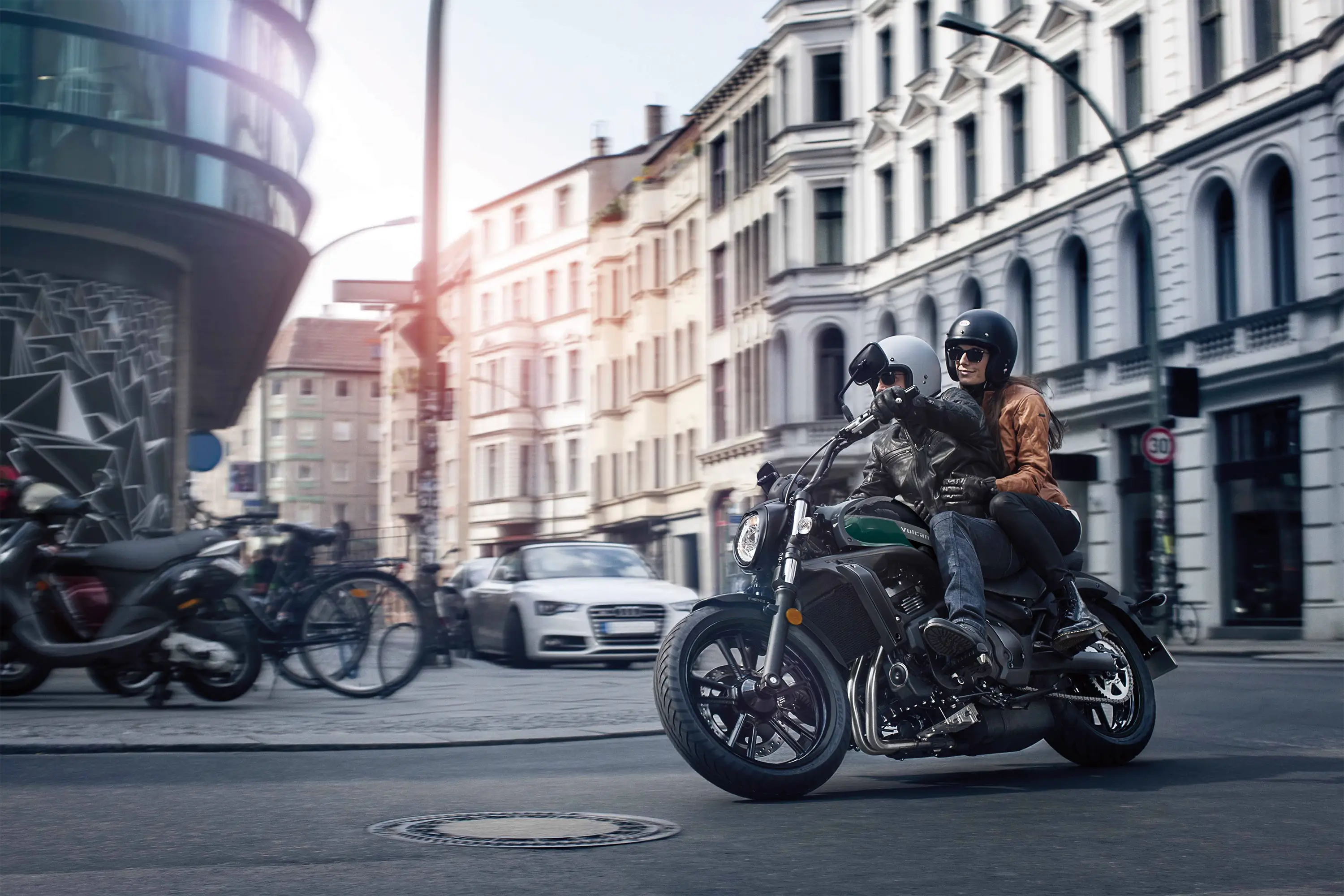 Three-quarter front angle of two people riding a motorcycle on the street.