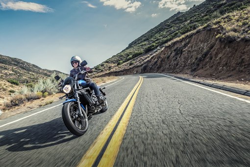 Three-quarter front angle of a person riding a motorcycle on a highway. opens in a new window
