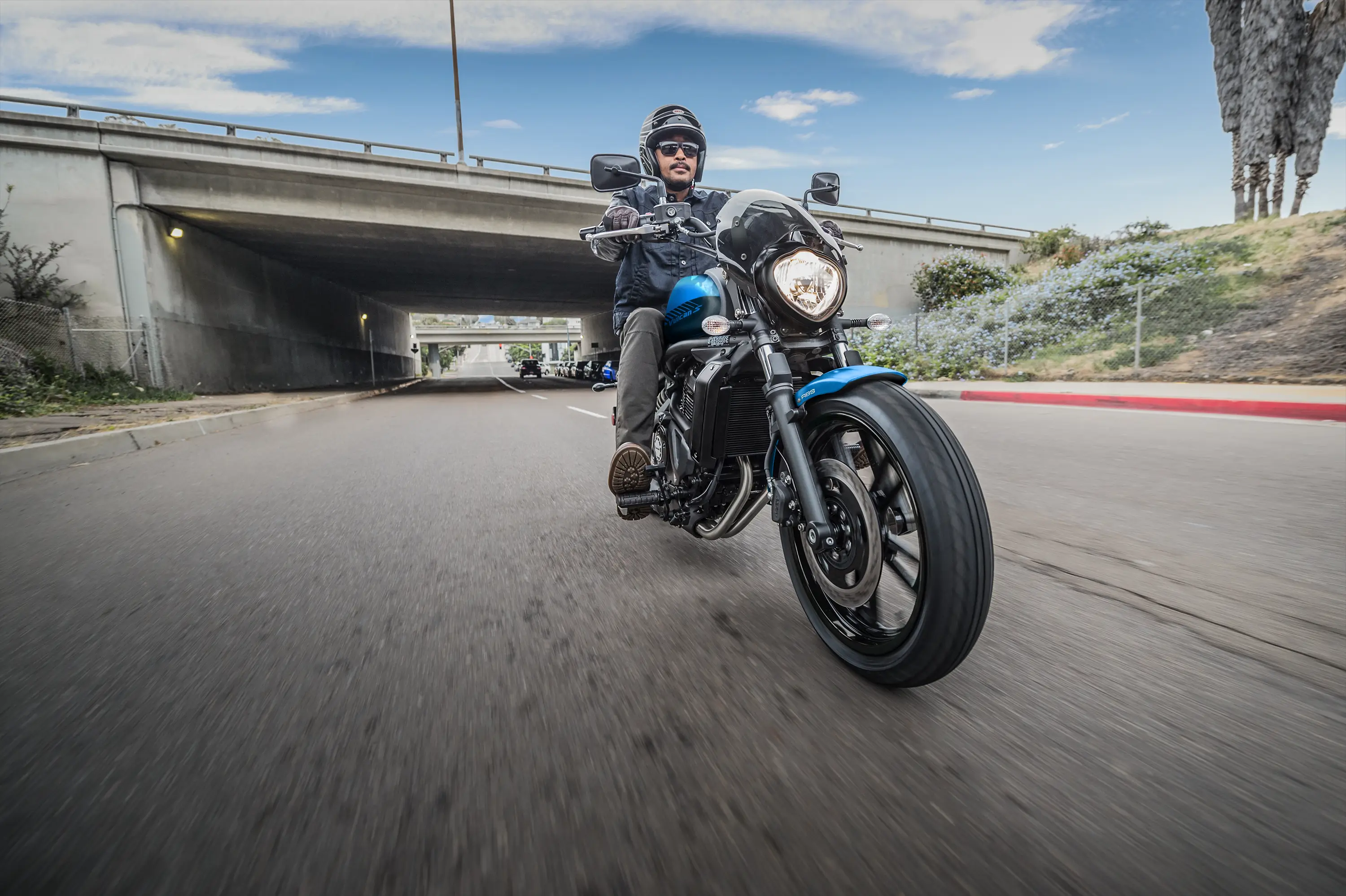 Three-quarter front angle of a person riding a motorcycle on the street.