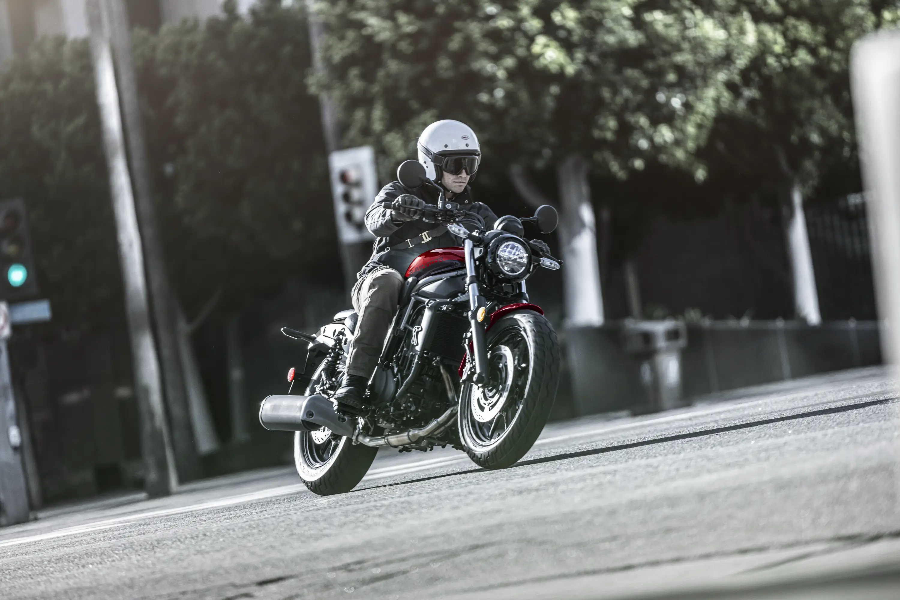 Three-quarter front angle of a person riding a motorcycle on the street.