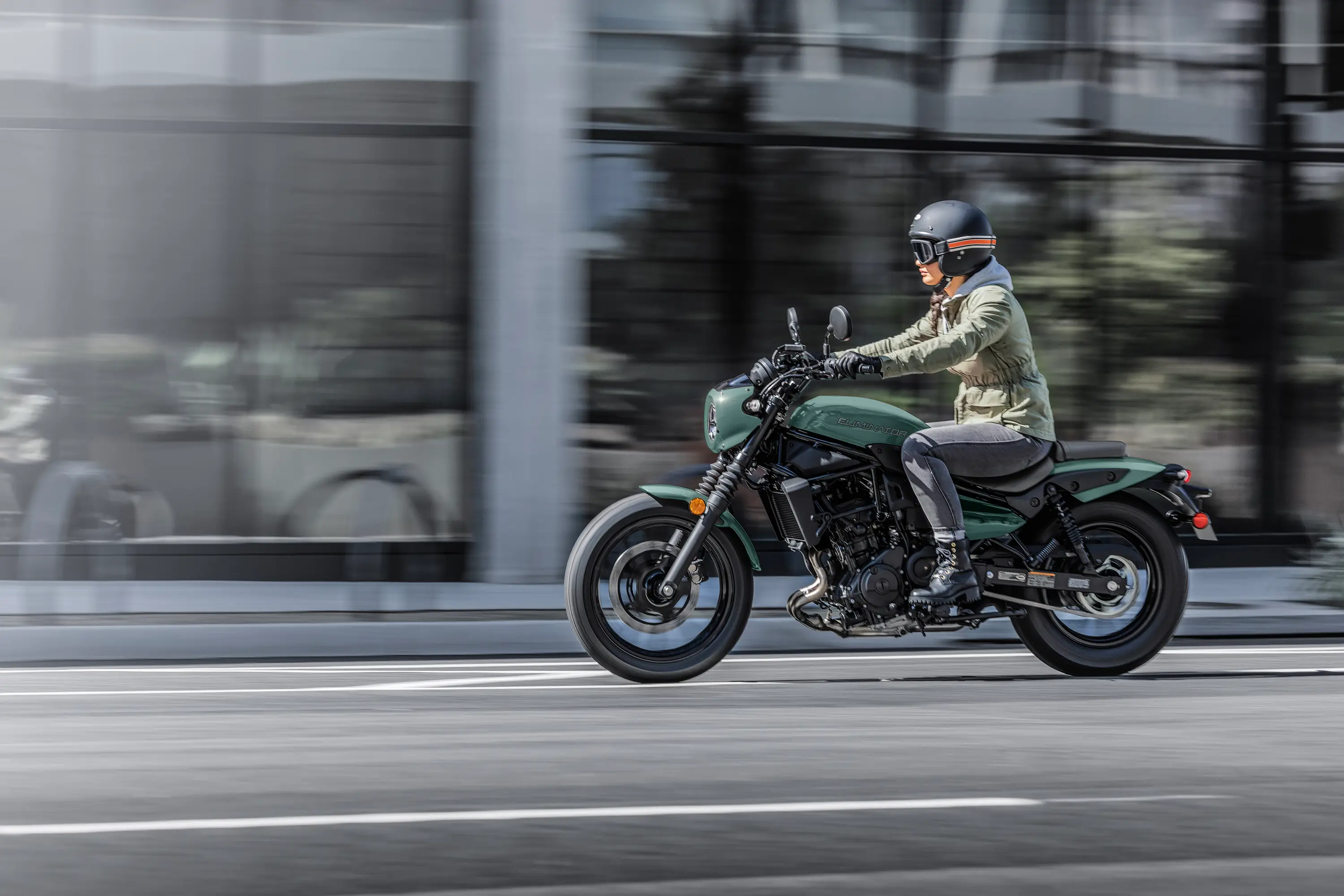 Side angle of a person riding a motorcycle on the street.