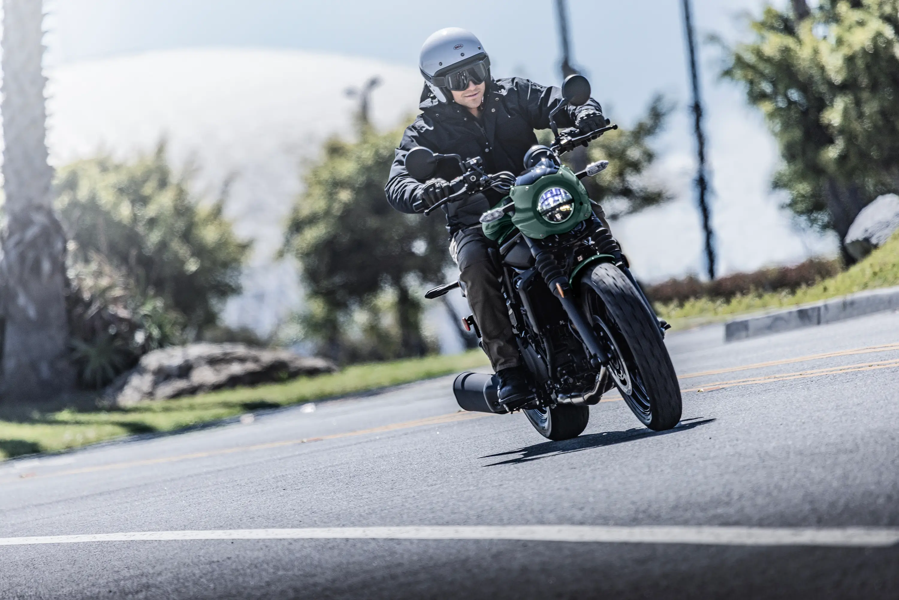 Three-quarter front angle of a person riding a motorcycle on the street.