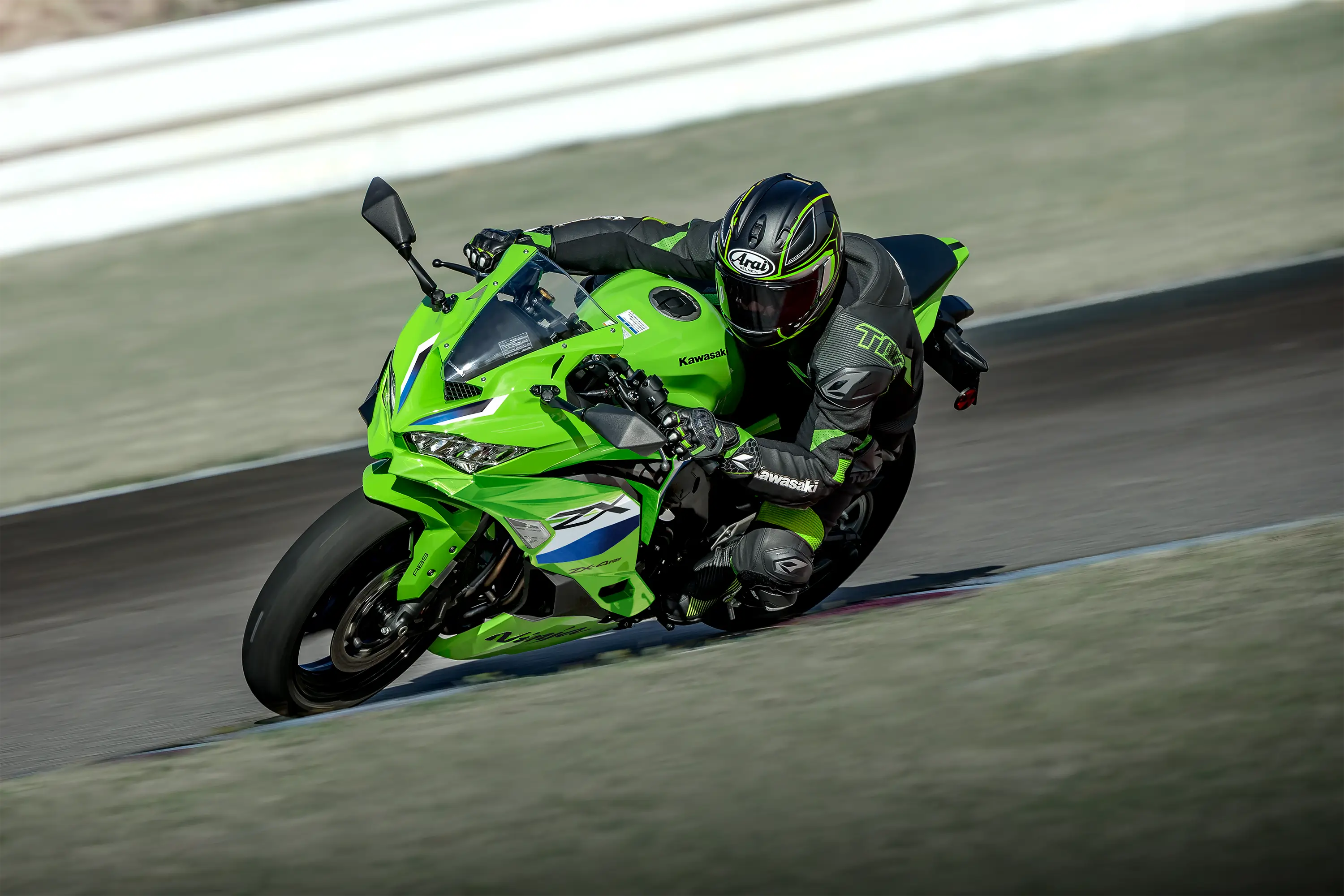Three-quarter front angle of a person riding a motorcycle on a racetrack.