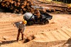 Side angle of a person driving a side x side on a job site.