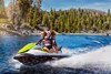 Three-quarter front angle of a person on a personal watercraft on the water by a forest. 