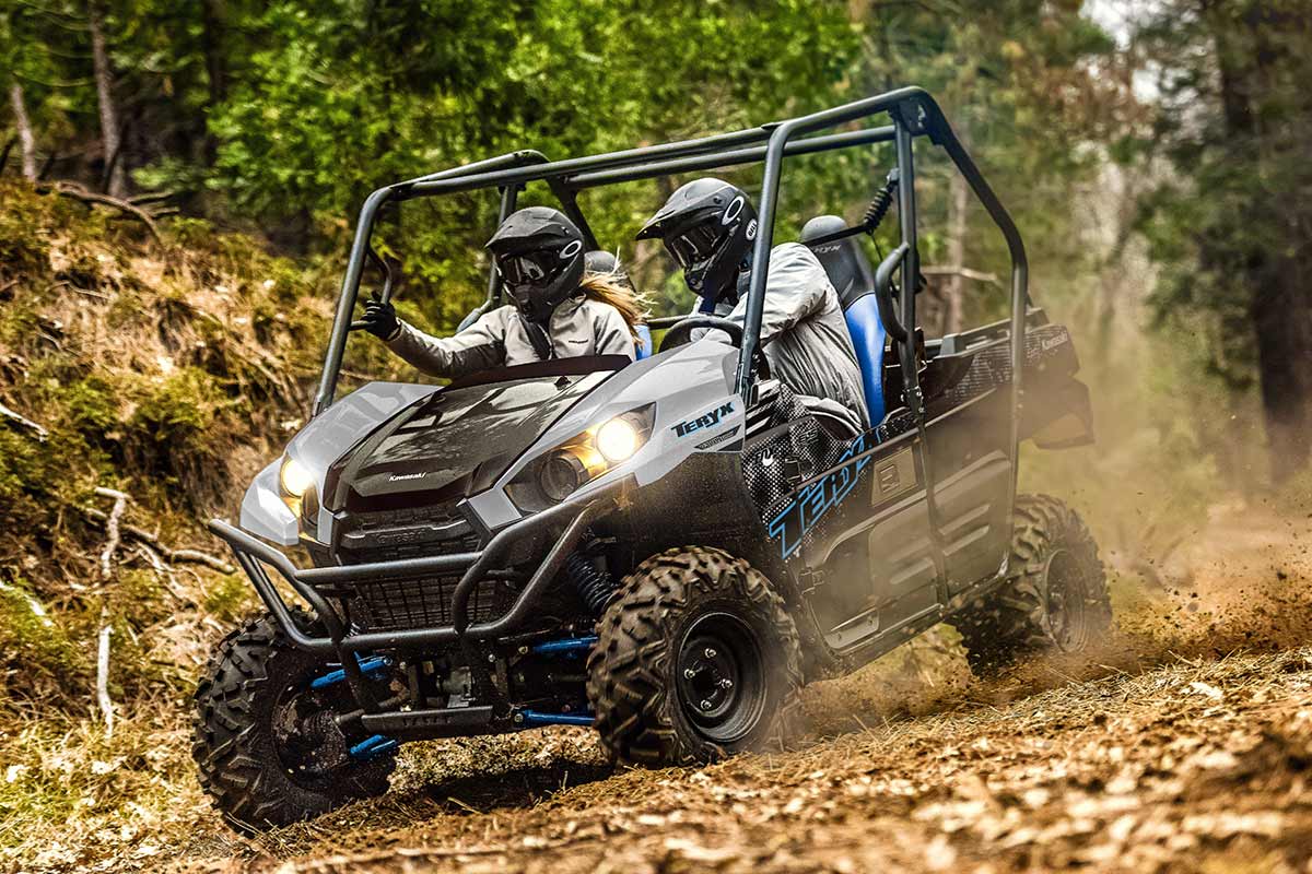 Three-quarter front angle of a person and passenger driving a side x side off-road down hill.