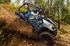 Side angle of a person and passenger driving a side x side off-road down hill.