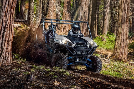 Three-quarter front angle of a person and passenger driving a side x side off-road. opens in a new window