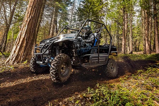 Side angle of a person and passenger driving a side x side off-road. opens in a new window