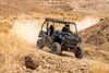 Three-quarter front angle of a person driving a side x side off-road around a corner.
