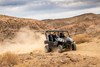 Three-quarter front angle of a person driving a side x side off-road.