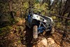 Front angle of a person and passengers driving a side x side off-road up hill.