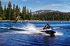 Three-quarter front angle of two people on a personal watercraft on a lake.