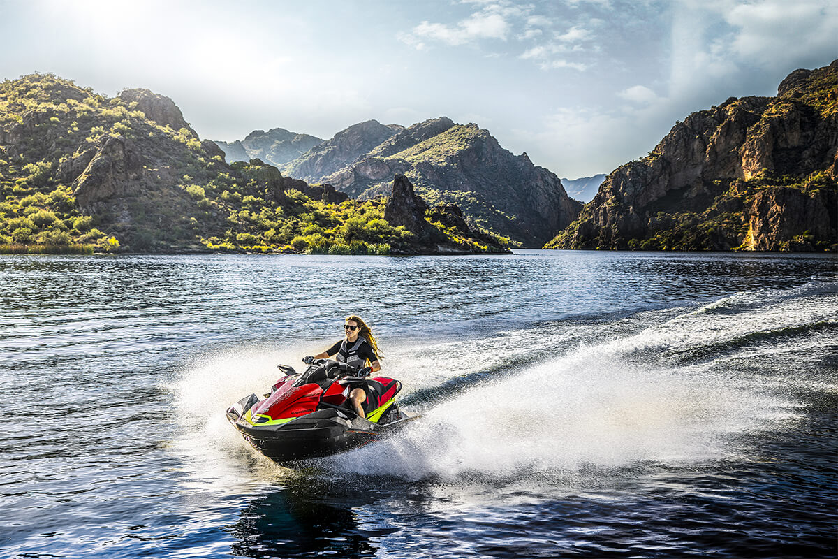 Three-quarter front angle of a person riding a personal watercraft on a lake.