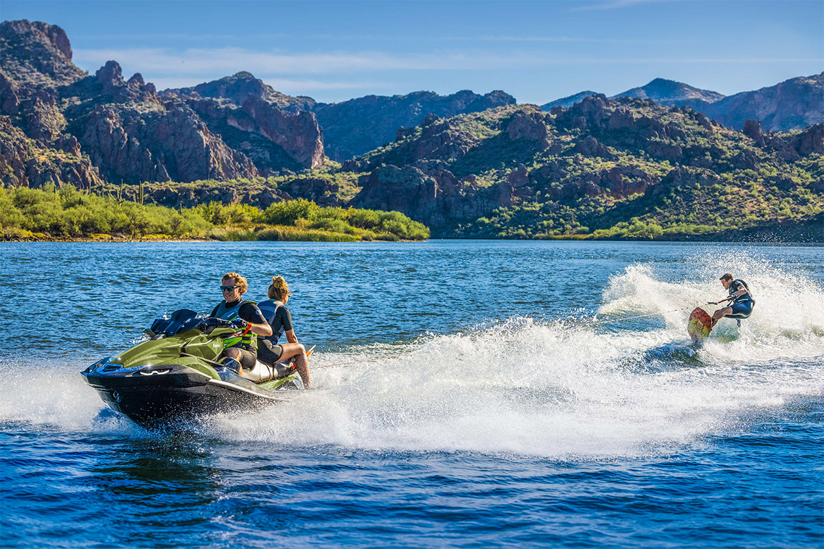 Three-quarter front angle of two people pulling a water-boarder on a personal watercraft.