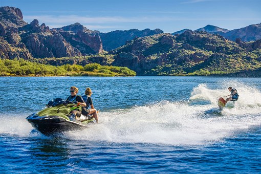 Three-quarter front angle of two people pulling a water-boarder on a personal watercraft. opens in a new window