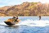 Three-quarter front angle of a personal watercraft pulling a skier on the water.