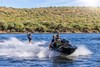 Three-quarter front angle of a personal watercraft pulling a skier on a lake. 