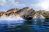 Side angle of a person riding a personal watercraft on a lake.