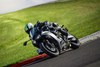 Three-quarter front angle of a person riding a gray motorcycle through a corner on a track.