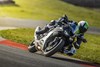 Three-quarter front angle of a person riding a motorcycle leaned over in a corner on a track.